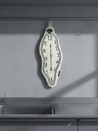 A DAMNART$ melting clock towel inspired by Dalí’s surrealist clocks, hanging on a minimalist grey kitchen wall beside a modern sink.