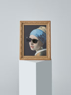 DAMNARTS Girl with a Pearl Earring glasses holder displayed on a pedestal, wearing black sunglasses, minimalist studio background.