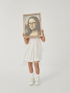 DAMNARTS Mona Lisa glasses holder lifestyle photo on white background, model holding the artwork with round optical glasses.