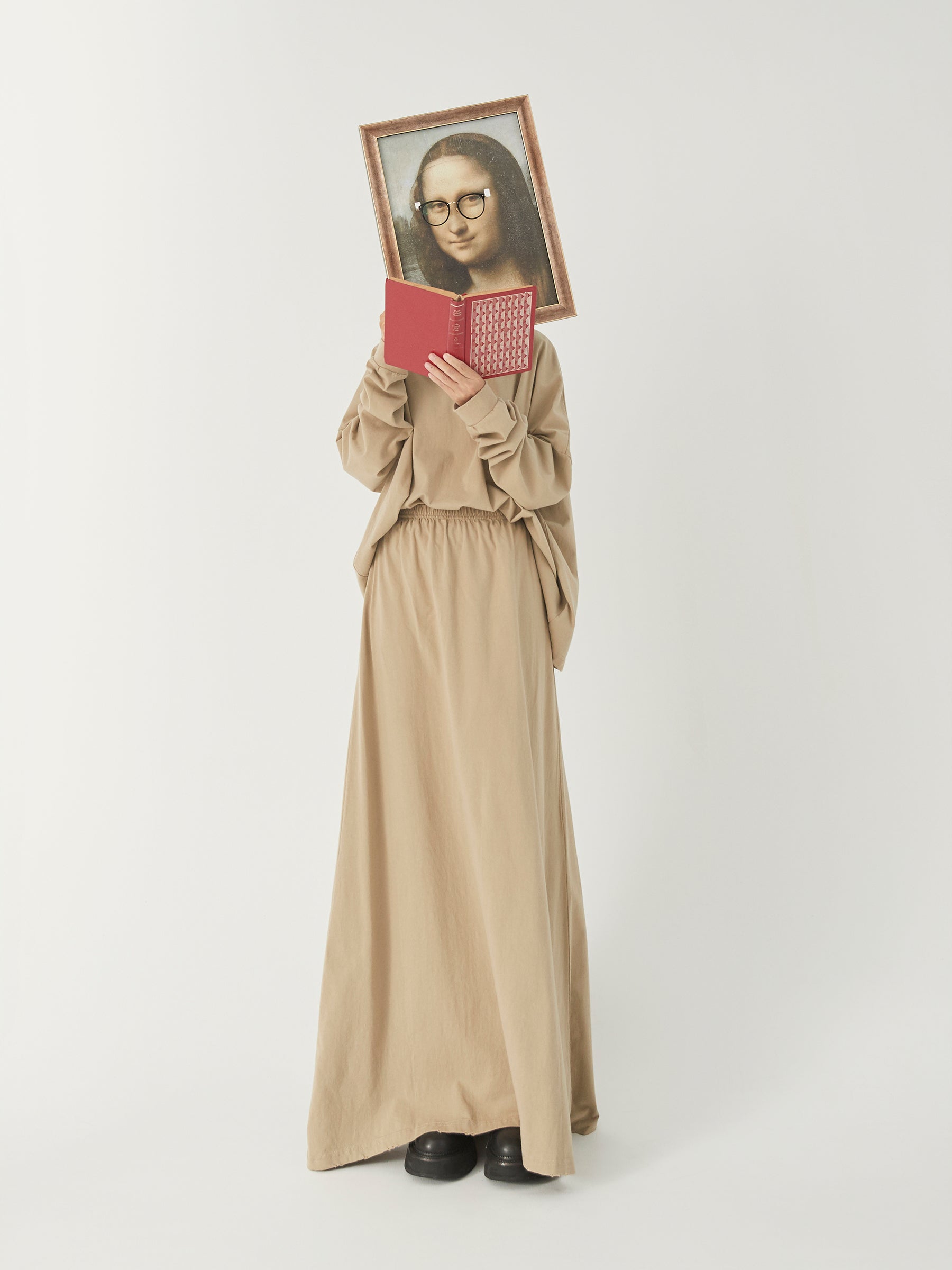 DAMNARTS Mona Lisa glasses holder lifestyle scene, model reading a book while holding the artwork with round glasses.