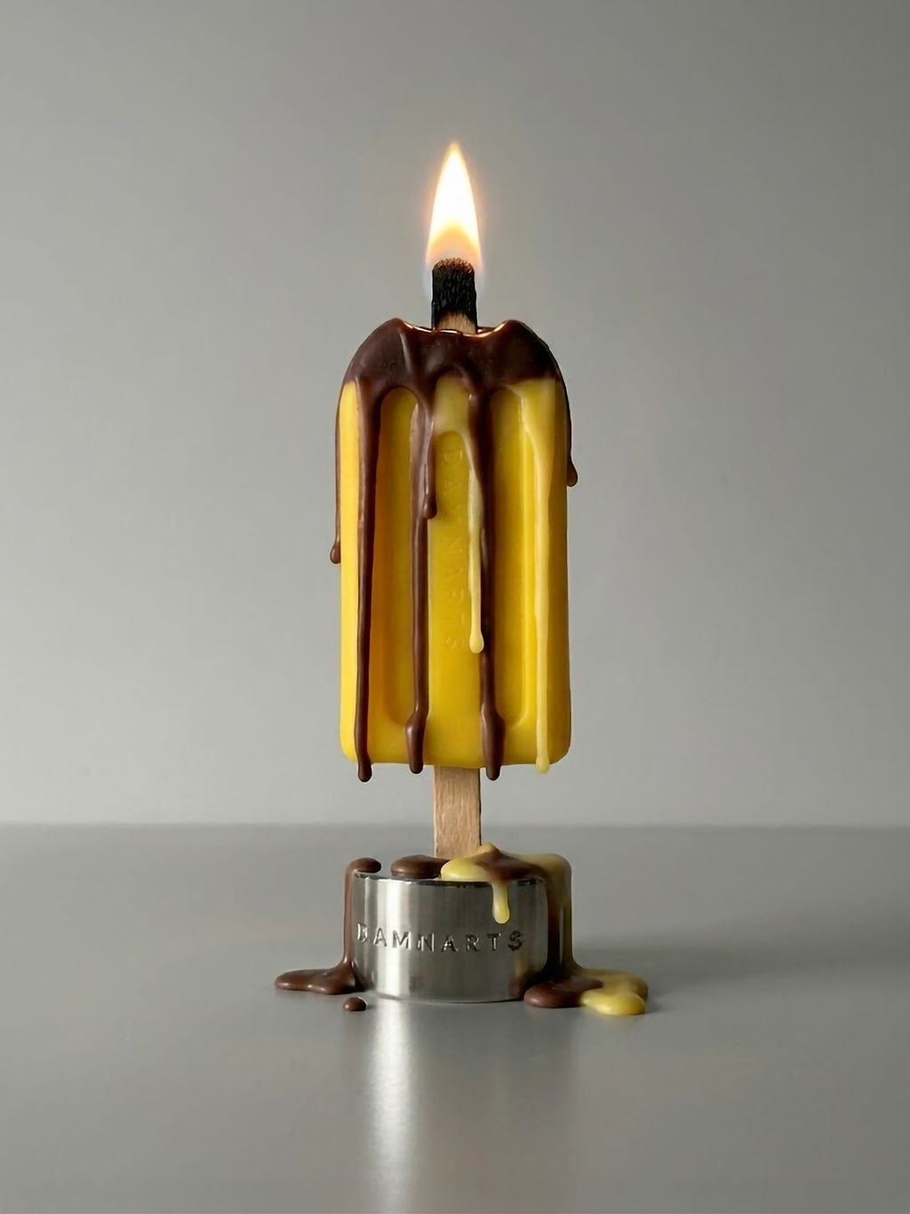 DAMNARTS Autumn Air scented ice pop candle burning with melting wax dripping
